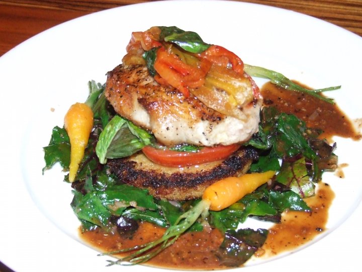Pork Loin sauteed with onions and peppers on top of fried Polenta with tomato and fresh Sweet Basil with summer time Greens and baby Carrots around.  Sauce drizzled around the plate.